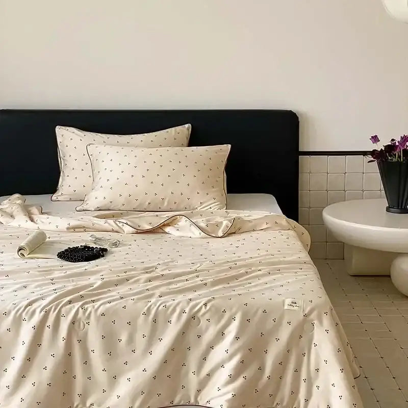 Cream-colored satin cooling quilt with delicate black floral embroidery for a restful night’s sleep by DecorBites