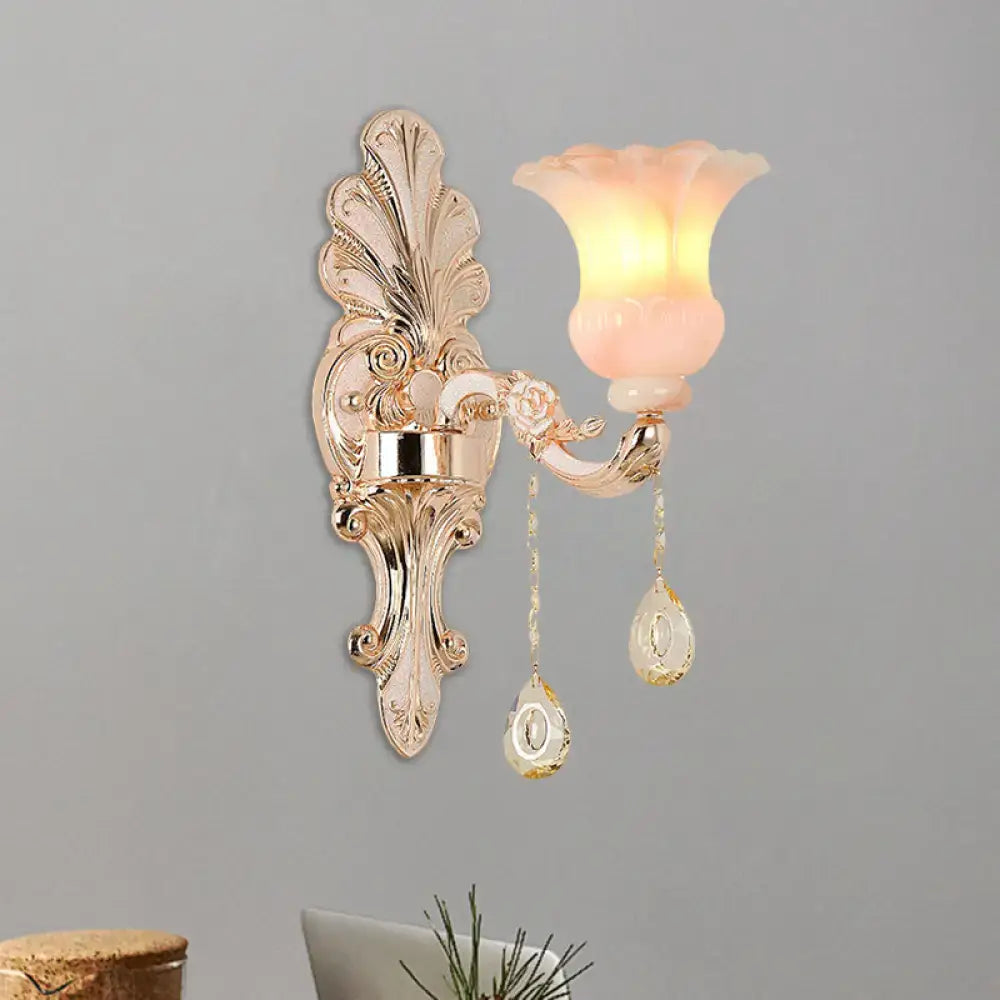 Chic gold and pink crystal wall lamp featuring an ornate gold-toned sconce with a translucent pink glass shade and crystal pendants