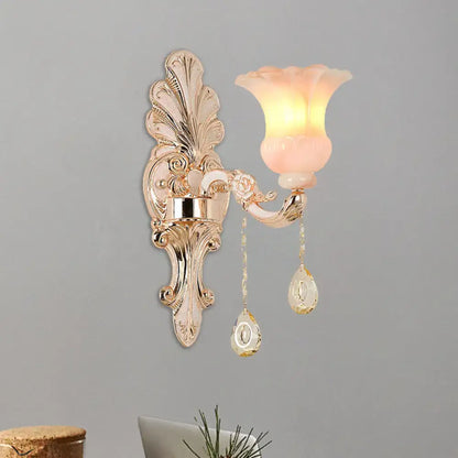 Chic gold and pink crystal wall lamp featuring an ornate gold-toned sconce with a translucent pink glass shade and crystal pendants