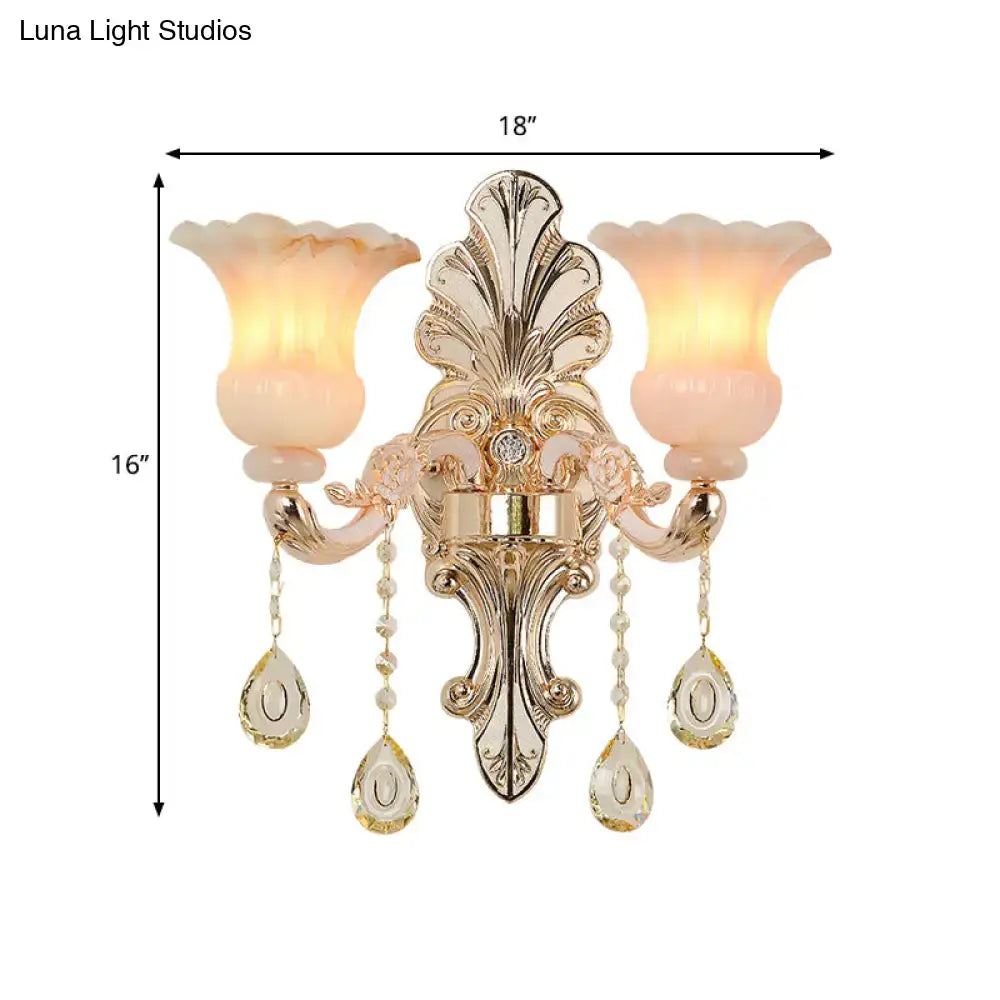 Gold-toned ornate wall lamp with two peach glass shades and crystal teardrop pendants for bedroom decor