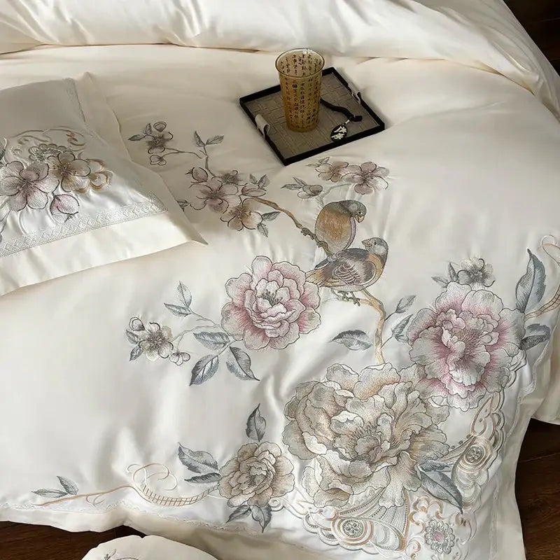Cream-colored satin duvet cover with intricate hand-embroidered chinese flowers bird motifs in soft pink beige tones