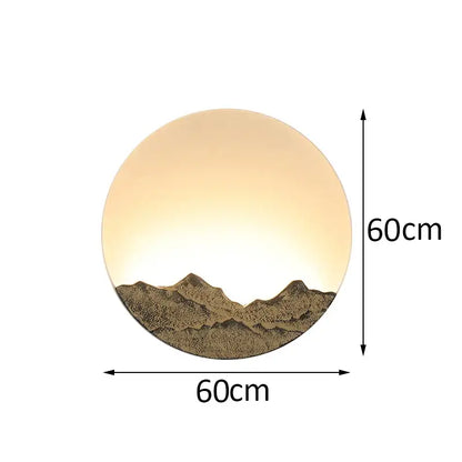 Circular bronze and gold decorbites led wall light with warm amber glow and textured mountain silhouette for living room