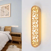 Chinese style beige carved wood wall light fixture with intricate scrollwork is a warm-toned bedroom wall sconce