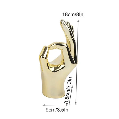 Golden metallic chrome ceramic love gesture figurine sculpture with polished reflective surface showing okay hand love gesture