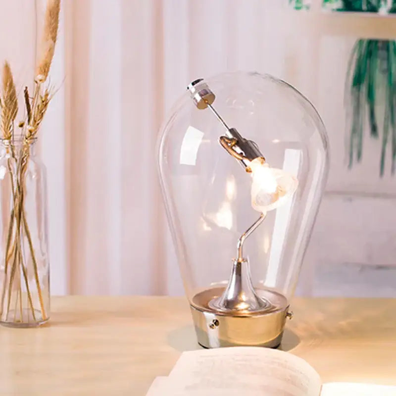 A clear glass bulb led table lamp with a brass base and exposed filament for bedroom use with a black shade