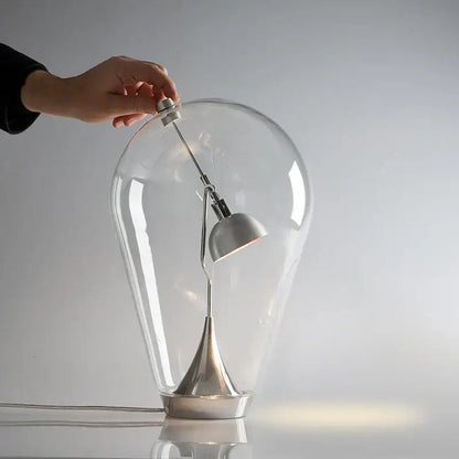 A sleek led table lamp with a transparent glass dome, polished chrome curved arm, and black shade for bedroom use