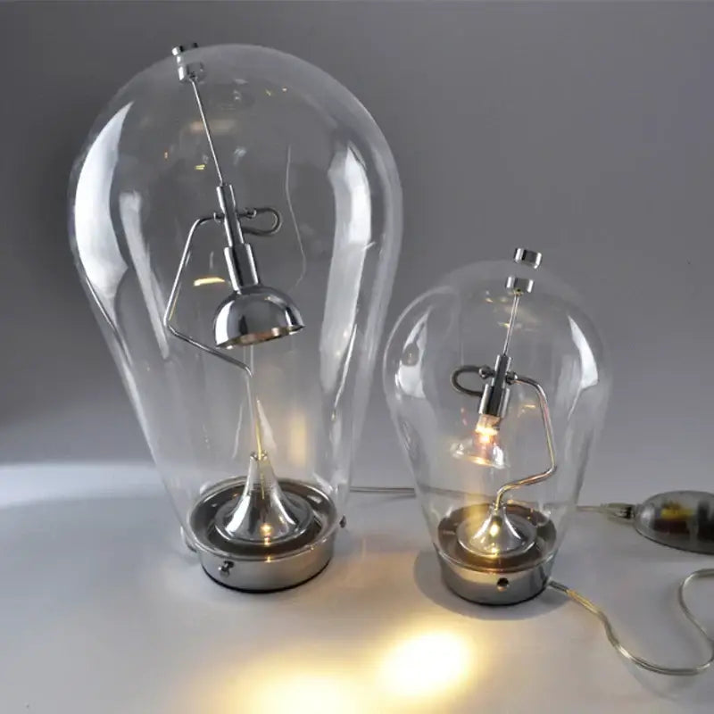 Two clear glass bulb led table lamps with chrome bases and adjustable curved arms for bedroom use