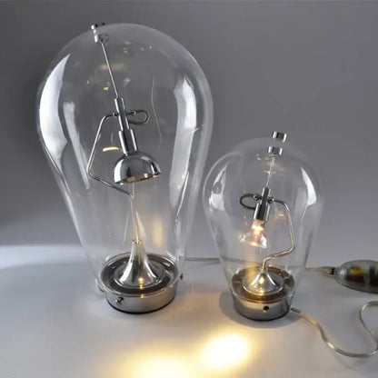 Two clear glass bulb led table lamps with chrome bases and adjustable curved arms for bedroom use