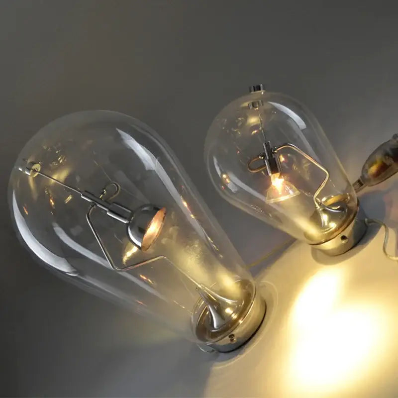 Two vintage-style glass incandescent bulbs with brass bases emitting warm glow in a chrome curved arm led table lamp
