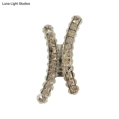 A sparkling silver h-shaped hair clip with clear faceted crystals matching chrome curvy crystal prism wall sconce design