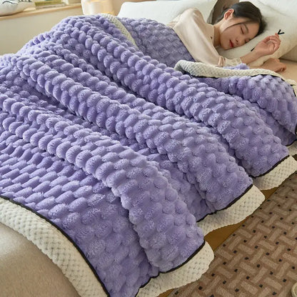 A plush lavender coral fleece blanket with raised dot pattern and cream trim for cozy bedroom use