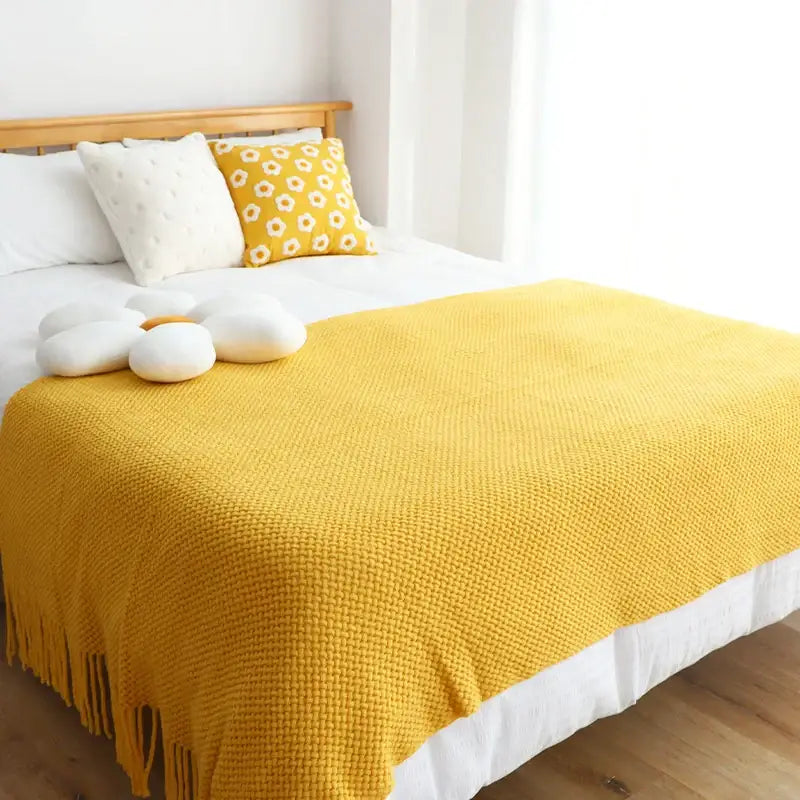 A cozy mustard-yellow decorbites knitted leisure blanket with textured weave and tassels for bedroom and living room decor