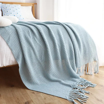 A soft light blue decorbites knitted leisure blanket with waffle pattern and tassels for bedroom and living room decor