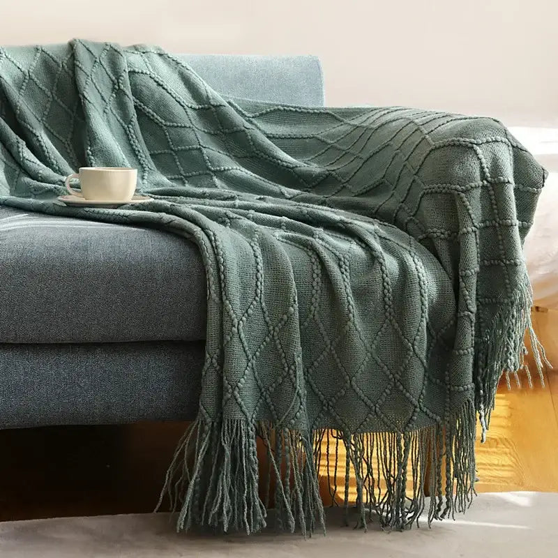 A cozy knitted sofa blanket in moss green with a diamond pattern and fringe for living room decorbites comfort