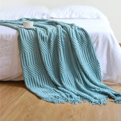 A soft teal knitted sofa blanket with a textured diamond pattern and fringed edges perfect for decorbites cozy knitted decor