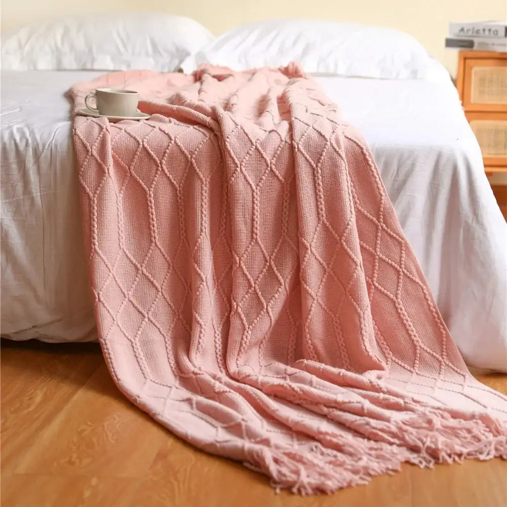 A soft pink cozy knitted sofa blanket with diamond pattern and fringed edges for decorbites cozy knitted living room comfort