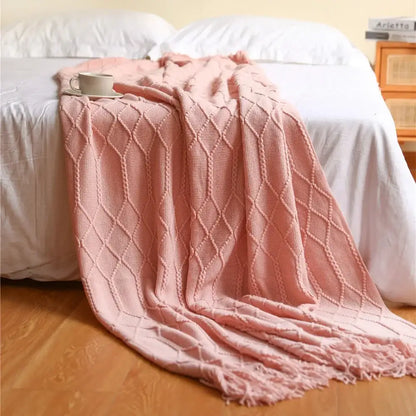 A soft pink cozy knitted sofa blanket with diamond pattern and fringed edges for decorbites cozy knitted living room comfort