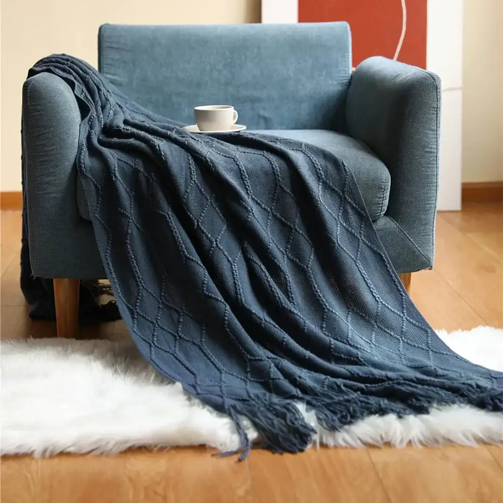Dark blue chunky ribbed cozy knitted sofa blanket with diamond pattern and fringed edges for living room comfort