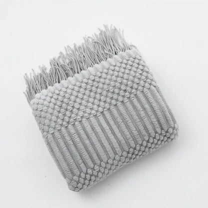 A soft light gray cozy knitted sofa blanket with raised dot texture and fringed edges for living room decorbites comfort