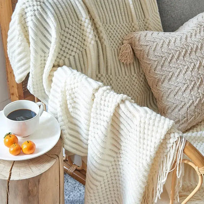 Cream-colored chunky ribbed knitted sofa blanket with textured patterns and fringe for decorbites cozy knitted decor