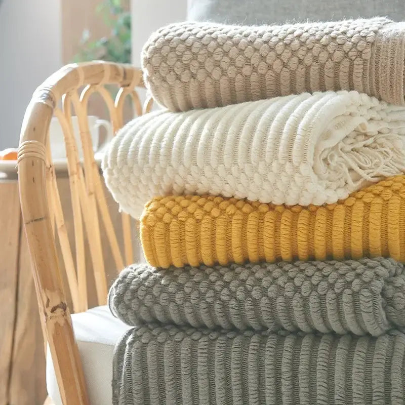 Stack of chunky ribbed neutral and mustard knitted sofa blankets showcasing cozy knitted decorbites living room comfort