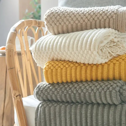 Stack of chunky ribbed neutral and mustard knitted sofa blankets showcasing cozy knitted decorbites living room comfort