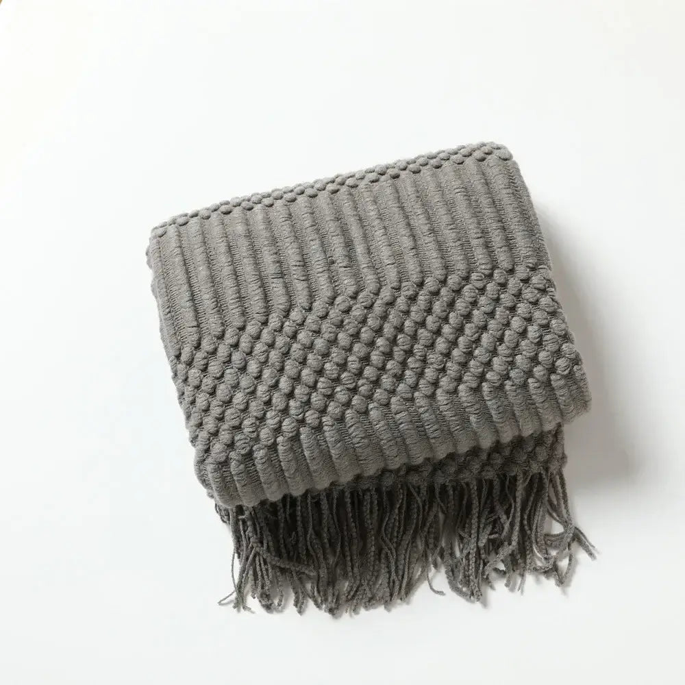 Gray chunky ribbed neutral knitted sofa blanket with fringe detailing for decorbites cozy knitted living room comfort