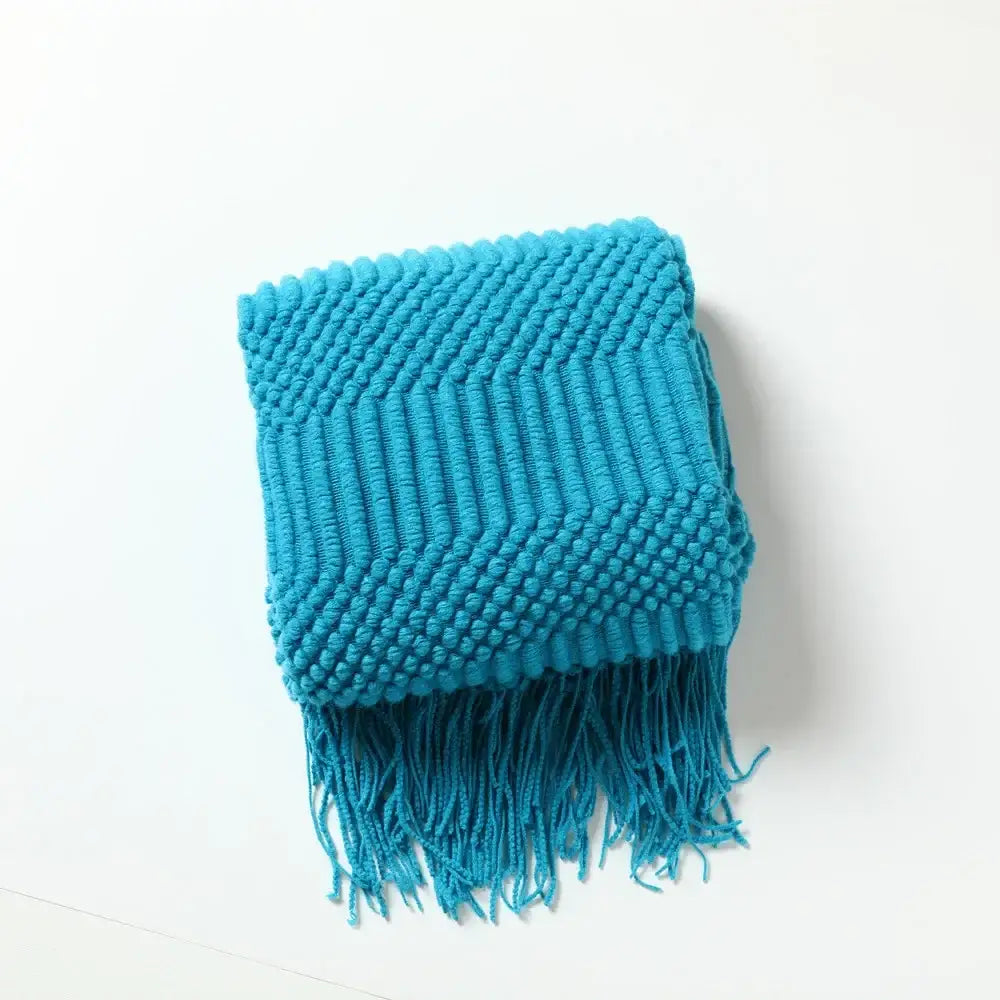 A vibrant turquoise cozy knitted sofa blanket with a chunky ribbed pattern and fringe for living room comfort decorbites
