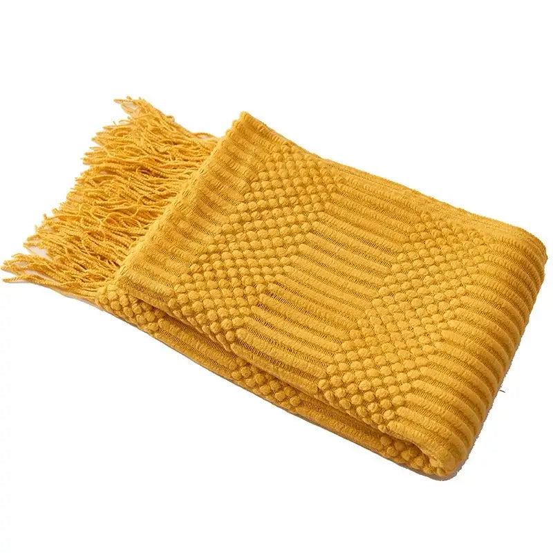 A cozy knitted sofa blanket in mustard yellow with chunky ribbed texture and fringed edges for living room comfort