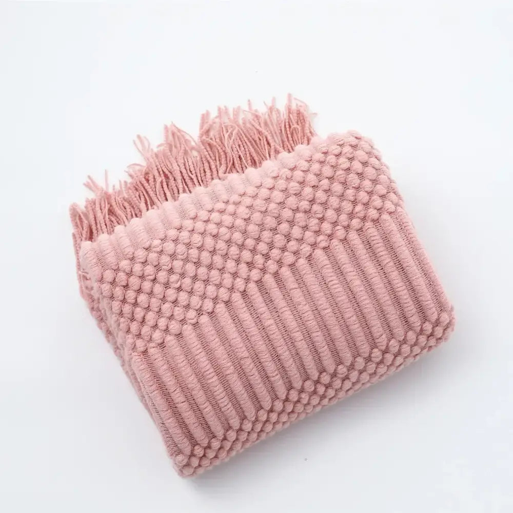 A soft pink cozy knitted sofa blanket with chunky ribbed texture and fringed edges for living room decorbites comfort