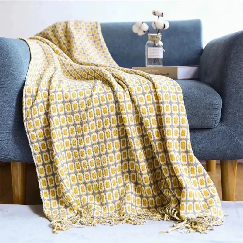 A cozy mustard-yellow and gray geometric throw blanket with fringed edges draped over a blue armchair for decorbites houndstooth throw