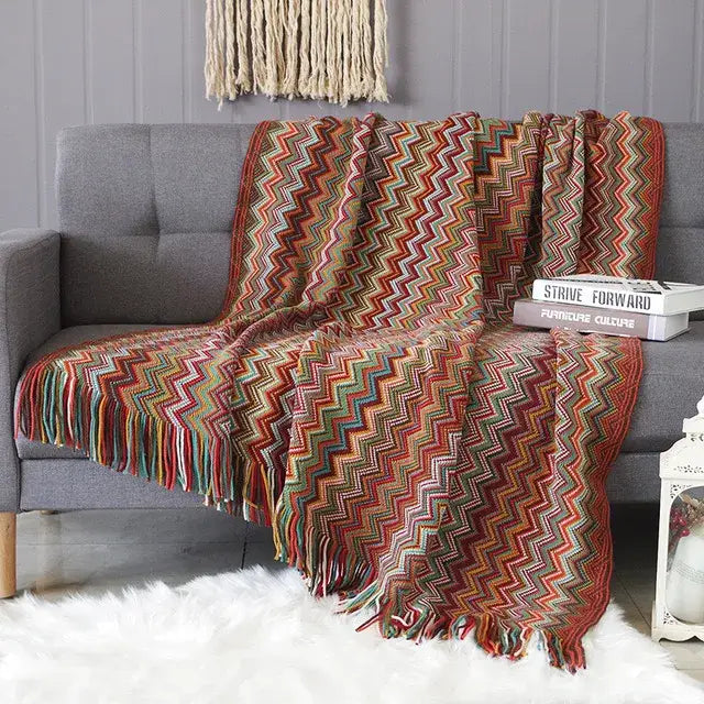 A vibrant multicolored zigzag patterned throw blanket with fringe detailing contrasting decorbites houndstooth throw blanket