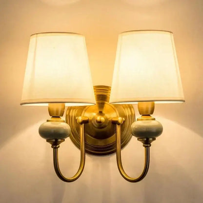 Brass-finished wall light with cream cloth cover shades and ceramic accents ideal for bedroom decorbites cloth cover wall use