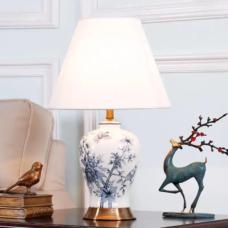 Classic white and black porcelain table lamp featuring a white porcelain table lamp with blue floral and bird designs and gold-tone base
