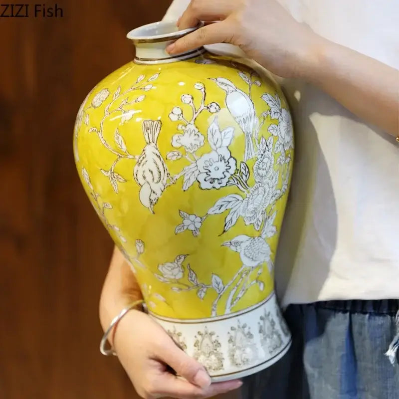 A vibrant yellow ceramic vase with white floral and bird motifs, gold-trimmed rim, for decorbites blue white porcelain decor