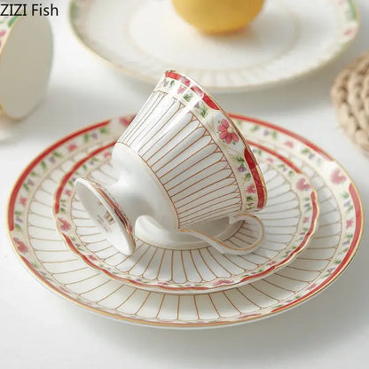 Delicate white porcelain ceramic cup with pink floral motifs and gold trim in classical gold-striped saucer set