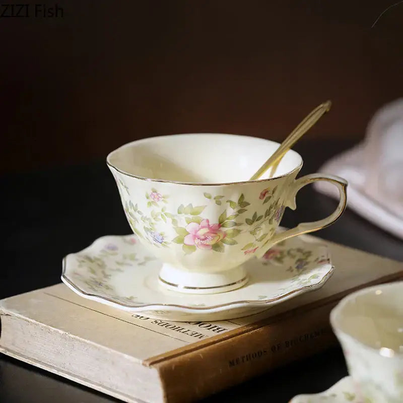 Delicate cream-colored classical ceramic cup with floral pattern and gold trim resting on matching saucer for dining decor