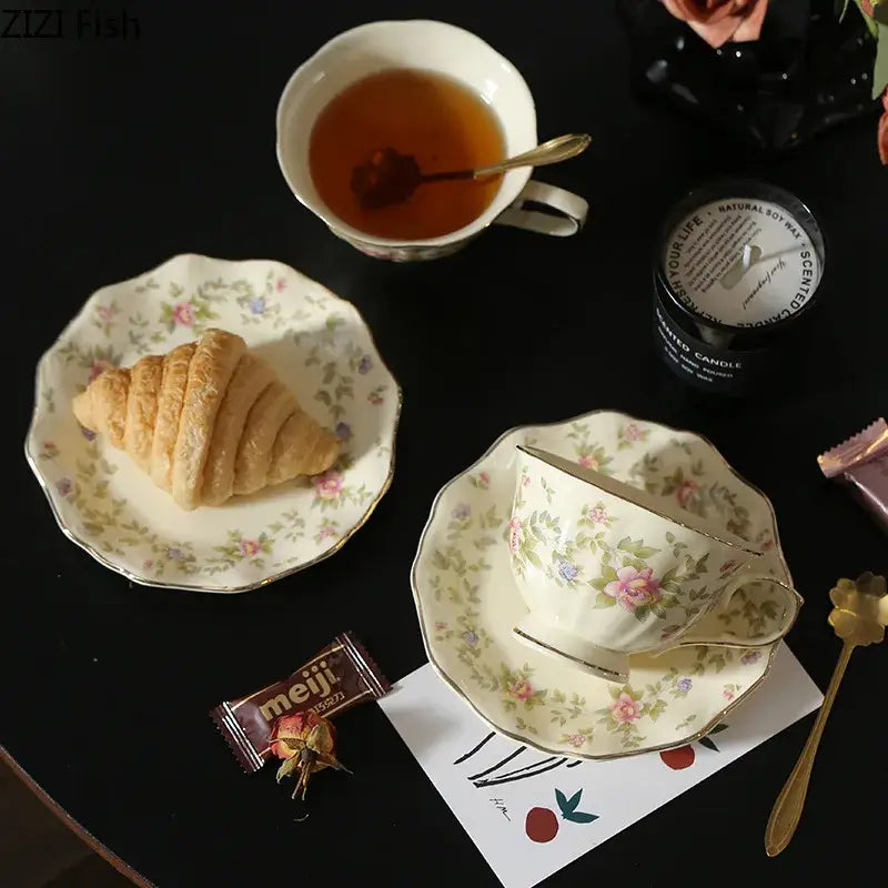 Cream-colored classical ceramic cup and saucer set with gold trim and delicate pink rose floral patterns for dining decor