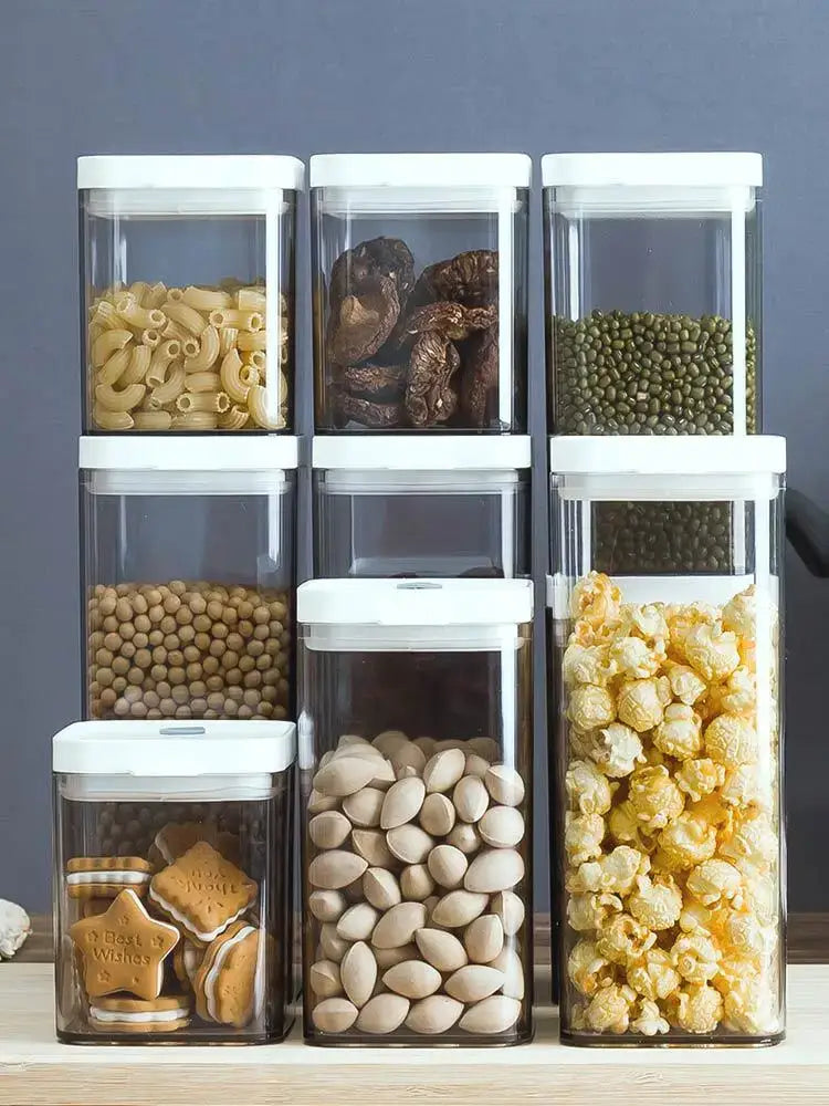 Clear bulk hermetic food storage containers with white lids holding pasta nuts and popcorn for kitchen organization