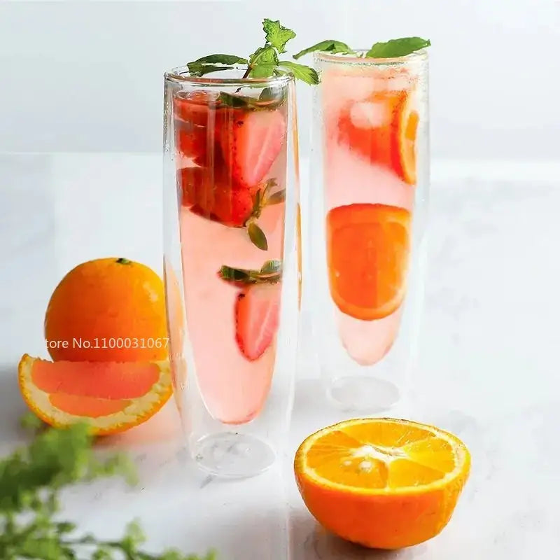 Two clear double wall stemless champagne glasses filled with pink beverages garnished with strawberries mint and orange slices