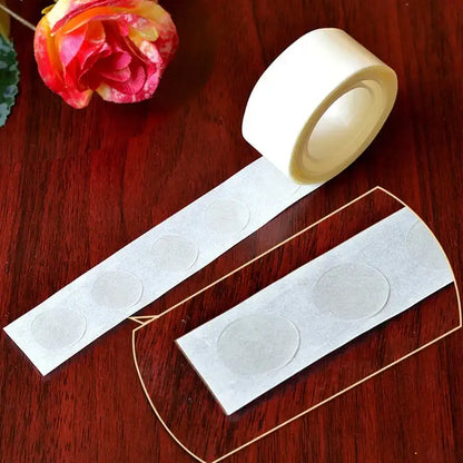 A roll of clear adhesive dots on white backing for use in clear embossed plastic balloon arch garland kit party decor