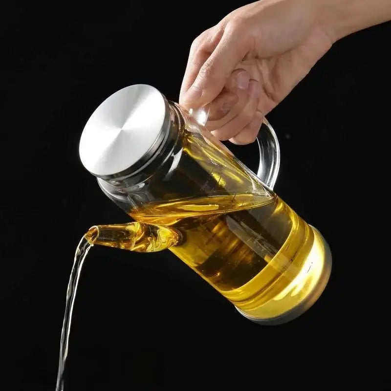 Clear glass and silver condiment bottle set featuring a transparent oil dispenser filled with golden-yellow oil