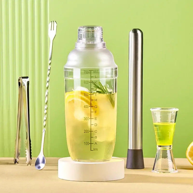 Clear glass cocktail shaker with silver lid filled with lemon slices and herbs ideal as a decorbites cocktail shaker beverage mixer