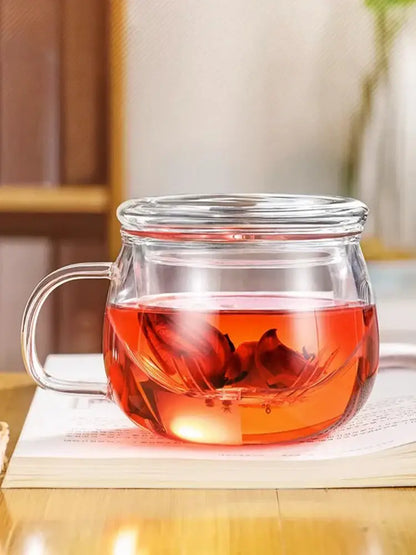Clear glass floral tea cup with filter and lid filled with vibrant red rose tea for kitchen teaware use