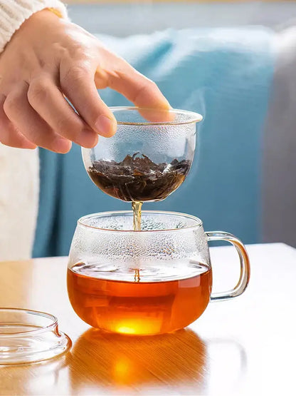Clear glass floral tea teapot with textured surface and handle filled with amber tea for elegant kitchen use