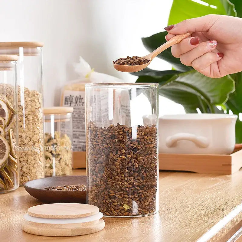 Clear glass storage jar with bamboo lid and wooden spoon filled with brown grains for kitchen organization