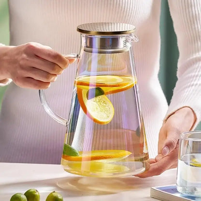Clear gold glass juice kettle set with citrus-infused water in a glass juice kettle with gold-toned lid and handle