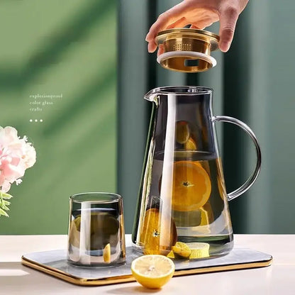 Clear gold glass juice kettle set featuring a clear glass pitcher with gold-toned lid and handle filled with sliced citrus