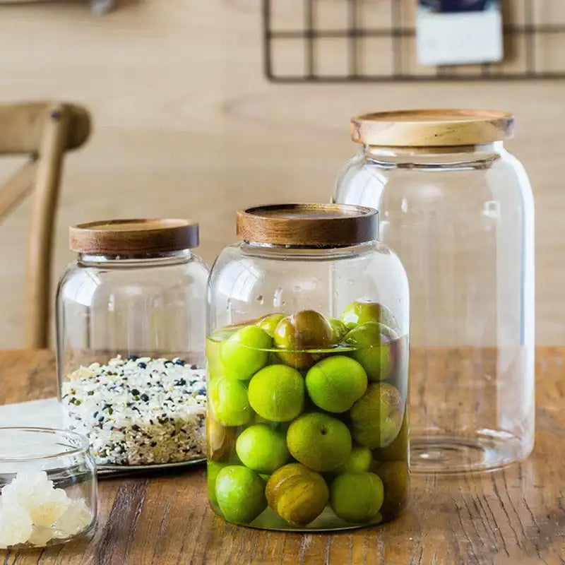 Clear kitchen glass jars with acacia lids set of 2 containing green plums and mixed grains for food storage