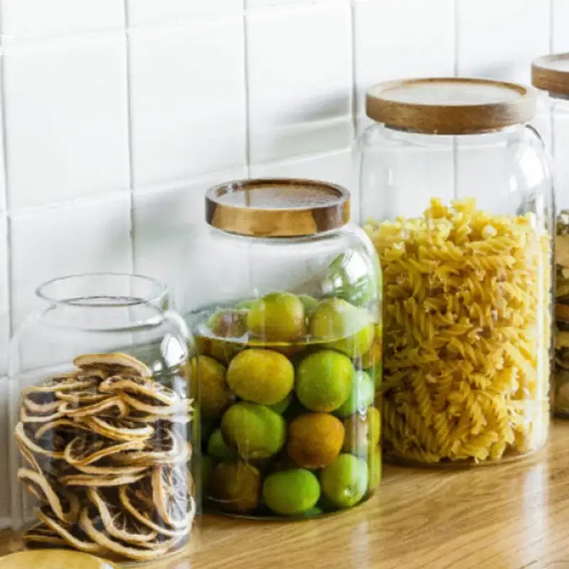 Clear kitchen glass jars set of 2 with acacia lids holding dried citrus slices and green fruits for food storage